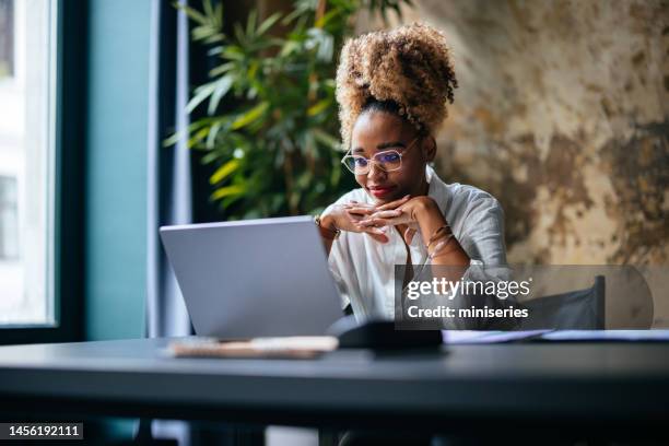 mujer de negocios sonriente usando una computadora portátil en el café - wear red day fotografías e imágenes de stock