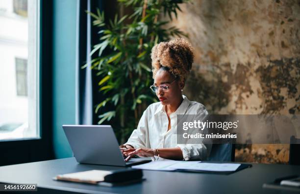 femme d’affaires utilisant un ordinateur portable dans le café - femme assise bureau photos et images de collection