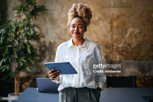 portrait of a smiling businesswoman using a digital tablet in the cafe - african american woman with tablet stockfoto's en -beelden