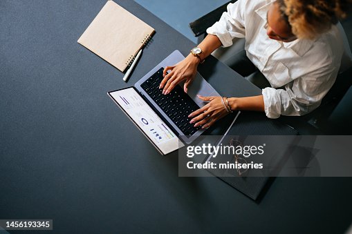 High Angle View Of Unrecognizable Woman Typing Business Report On A Laptop Keyboard In The Cafe High Angle View Of Unrecognizable Woman Typing Business Report On A Laptop Keyboard In The Cafe