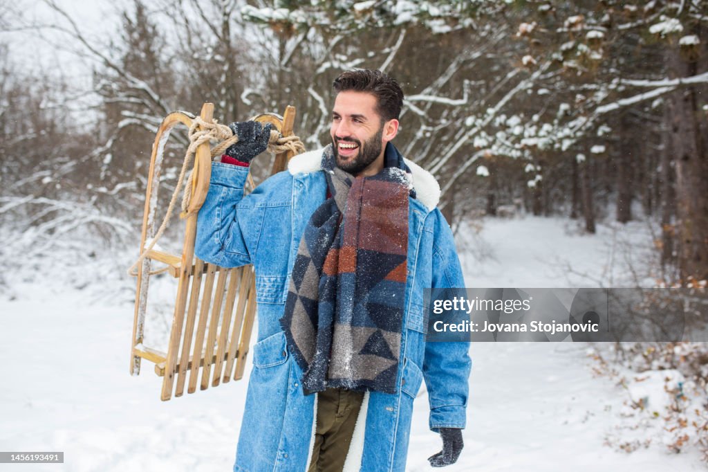 Man Riding Sled A Handsome Man With A Sled Enjoys The Snow And Sledding High-Res Stock ...