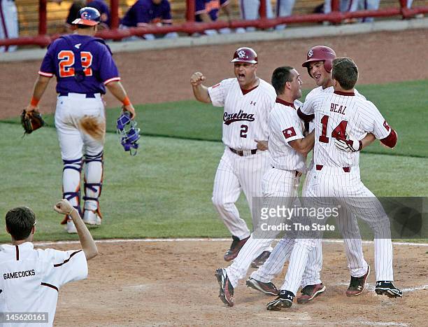 South Carolina's Joey Pankake celebrates with teammates T.J. Costen and Evan Beal after scoring the game-winning run in the 12th inning against...