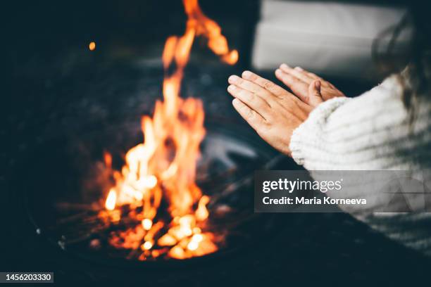 woman warming her hands at the fireplace. - drinking cold drink stock pictures, royalty-free photos & images