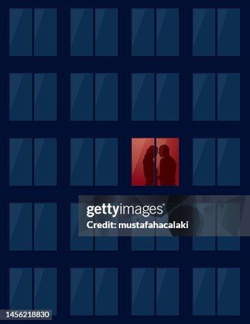 Lovers kissing in the illuminated window Lovers kissing in the illuminated window