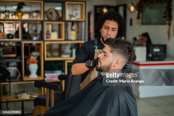 male stylist performs haircut to a client - hair salon stock pictures, royalty-free photos & images