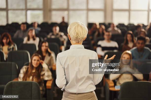 back view of a female professor teaching her students at lecture hall. - academia stockfoto's en -beelden