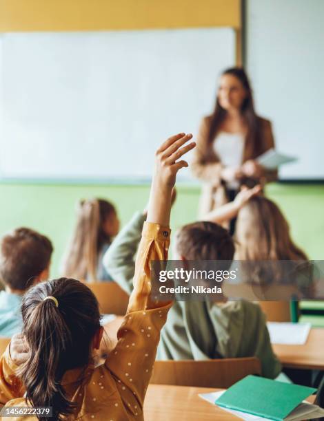 ragazza della scuola in classe che alza le mani per fare domande - school foto e immagini stock