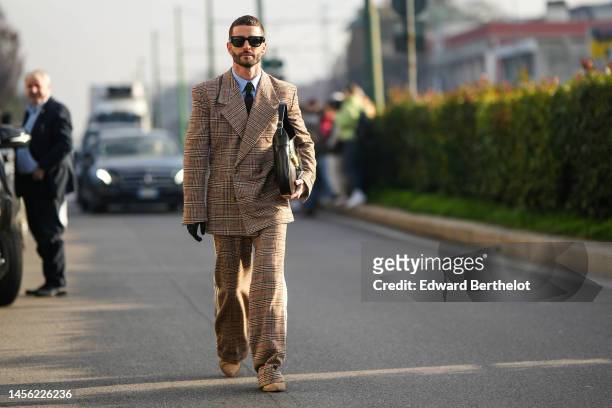 Pelayo Diaz wears sunglasses, a blue shirt, a tie, a Gucci oversized brown / beige blazer jacket with checkered patterns, matching suit flared pants,...