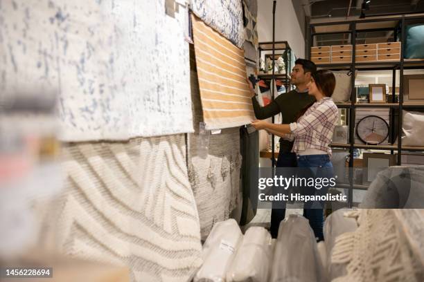 pareja feliz mirando alfombras en una tienda de muebles - sala de muestras fotografías e imágenes de stock