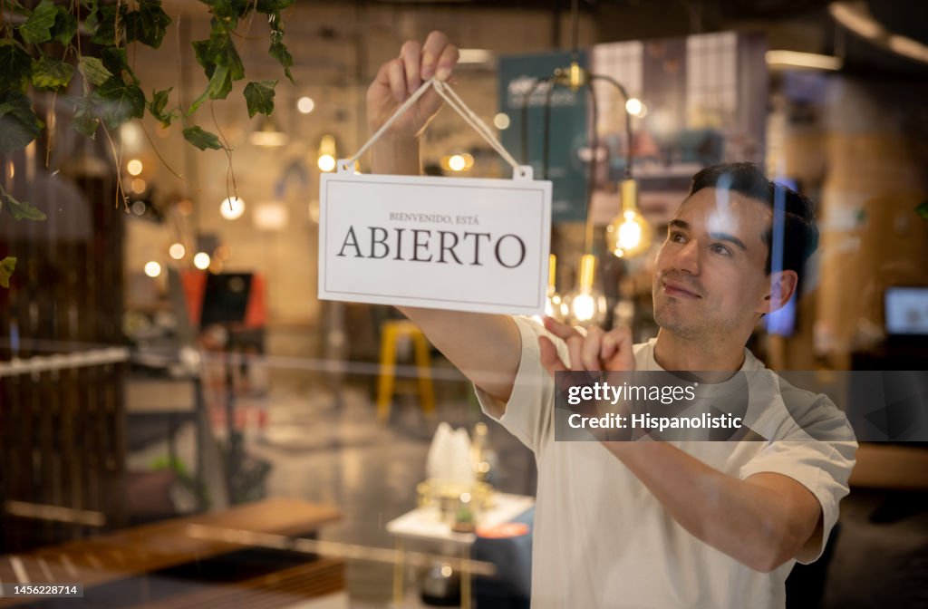 Empleado de venta colgando un cartel abierto en la puerta de una tienda de muebles