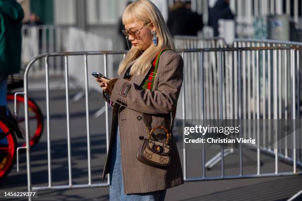 Guest wears brown Gucci blazer, bag, sunglasses, boyfriend je outside Gucci during the Milan Menswear Fall/Winter 2023/2024 on January 13, 2023 in...