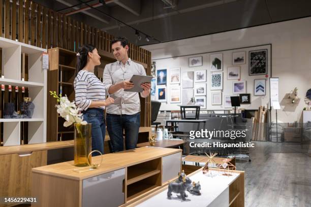 retail clerk helping a woman shopping at a furniture store - furniture store stockfoto's en -beelden