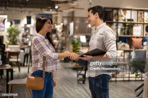 frau schüttelt einem einzelhandelskaufmann beim einkaufen in einem möbelhaus die hand - einzelhandel öffentliches gebäude stock-fotos und bilder