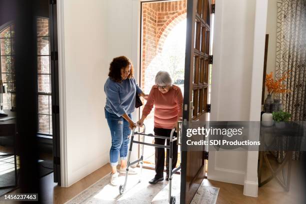 mid adult woman helps her senior adult friend - manutenção imagens e fotografias de stock