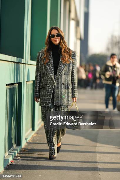 Tamara Kalinic wears black sunglasses with silver rhinestones from Gucci, silver earrings, a black turtleneck pullover, a gray wool and embroidered...