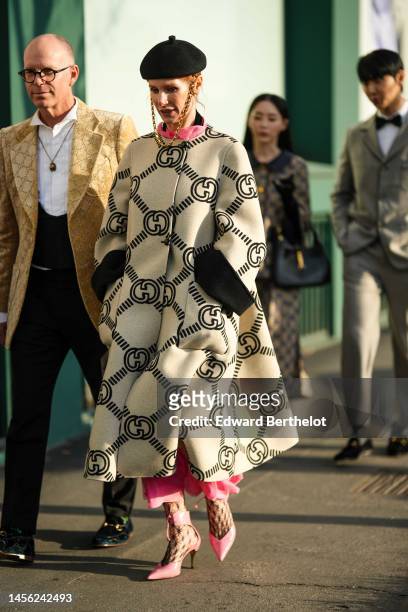 Guest wears a black felt wool beret hat with a gold large chain, a pink silk long dress, a white latte with black GG monogram print pattern long coat...