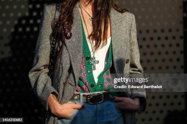 Guest wears a white tank-top, a gold chain and silver large cross pendant necklace, a green with pink print pattern buttoned cardigan, a gray and...