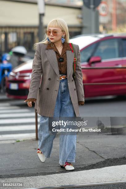 Guest wears orange sunglasses from Gucci, a blue velvet and gold embroidered stars pendant earrings, a gold necklace, a brown cut-out print pattern...