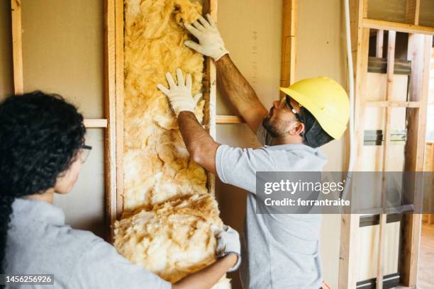 trabajadores de la construcción instalando aislamiento - buhardilla fotografías e imágenes de stock