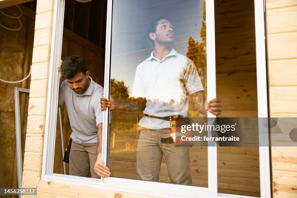 operai edili che installano finestre - installare foto e immagini stock