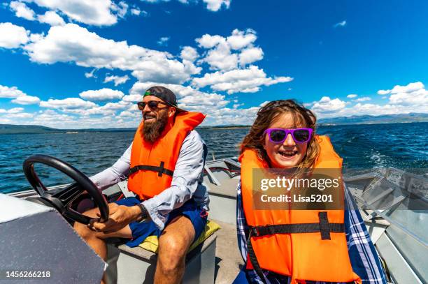 happy father and daughter wearing life jackets on a small motor boat on a scenic lake with his family, togetherness in nature - life jacket stockfoto's en -beelden