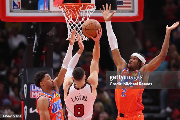 Zach LaVine of the Chicago Bulls shoots over Aaron Wiggins and Shai Gilgeous-Alexander of the Oklahoma City Thunder during the second half at United...