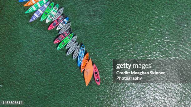 a line of canoes and kayak tied up together on the blue water of a river - brunswick heads nsw stock pictures, royalty-free photos & images