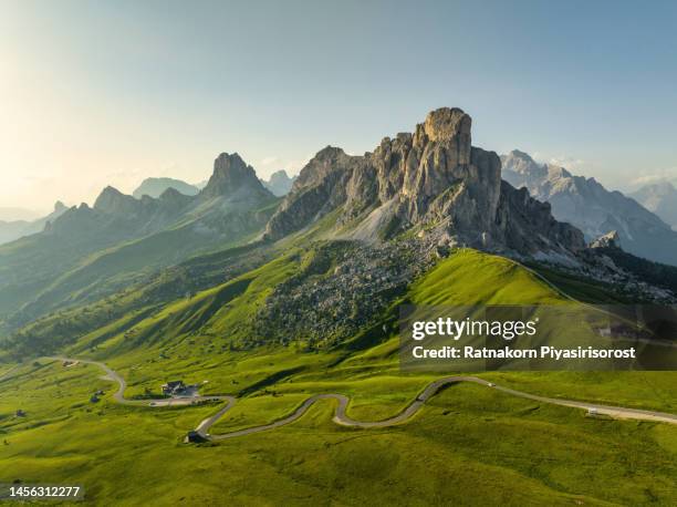 panoramic aerial drone flight video around trekker on green hill with beautiful sunset scene summer of dolomites alps mountain landscape. stunning giau pass - 2236m mountain pass in the province of belluno in italy - montagne photos et images de collection
