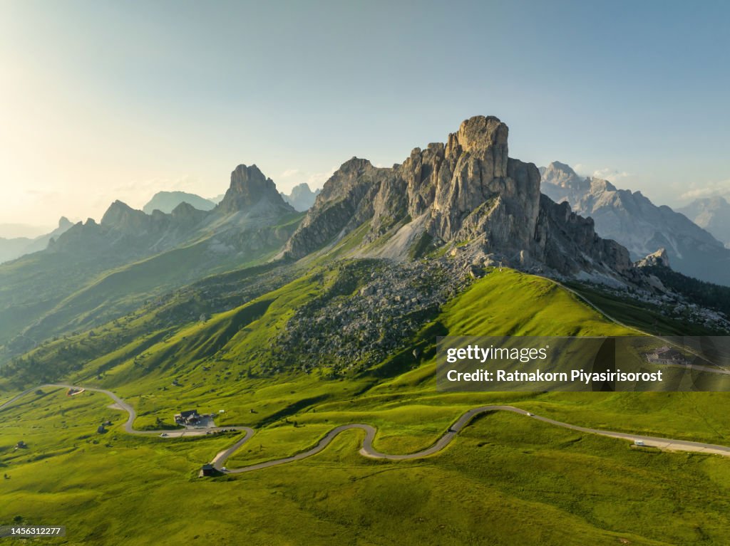 Panoramic aerial drone flight video around trekker on green hill with beautiful sunset scene summer of Dolomites Alps mountain landscape. Stunning Giau Pass - 2236m mountain pass in the province of Belluno in Italy