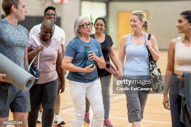 making friends at yoga class - healthy lifestyle senior stock pictures, royalty-free photos & images
