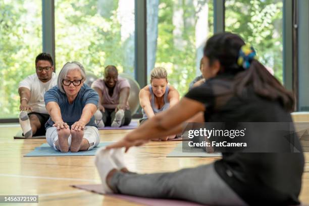 stretching in fitness class - sit ups stockfoto's en -beelden