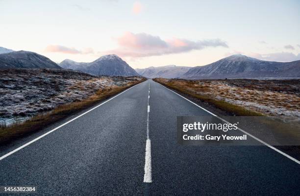 road leading into the distance in scottish highland winter landscape - roads stock-fotos und bilder