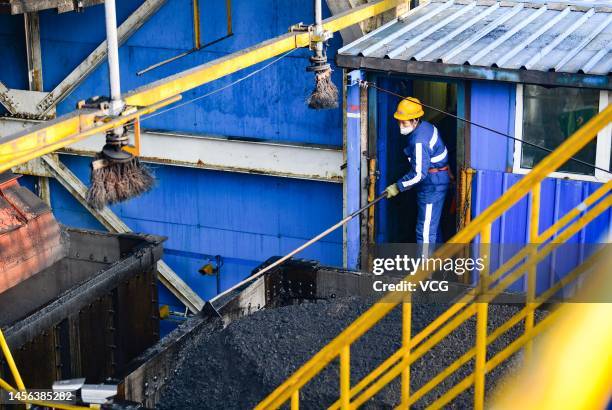An employee removes coal cinder from a freight train at a coal mine belonging to China Energy Investment Corporation on January 14, 2023 in Ejin Horo...