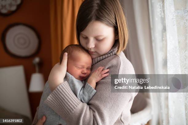 girl child teenager hugs and soothes newborn baby. - moms crying in bed stock pictures, royalty-free photos & images