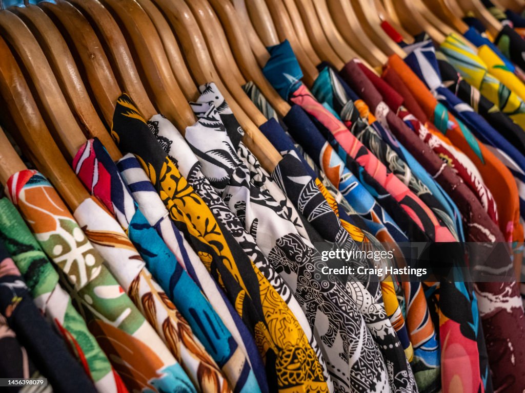 Close up of Stack of T-shirts on hangers and racks in department store in London, UK. Plain standard style Shirts in original stone wash and earthy colours and patterns