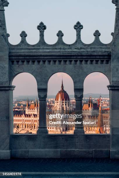 hungarian parliament building seen through arches of fishermen's bastion, budapest, hungary - budapest stock-fotos und bilder