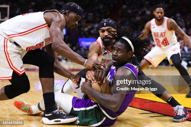 Jrue Holiday of the Milwaukee Bucks competes for a loose ball against Jimmy Butler and Gabe Vincent of the Miami Heat during the third quarter of the...