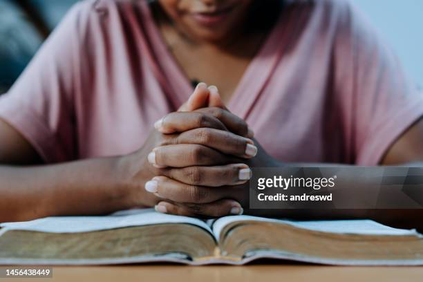 woman praying with the bible on the table - bidden stockfoto's en -beelden
