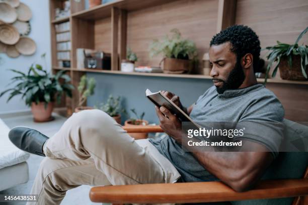 man reading the bible - bible stockfoto's en -beelden