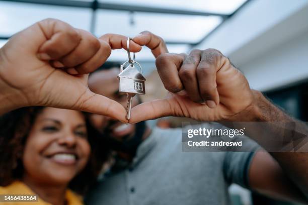 couple second key to new home with hand in heart symbol - homeowner stockfoto's en -beelden