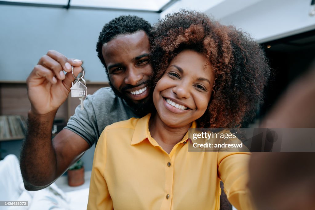 Pareja extasiada haciendo selfie en una casa nueva