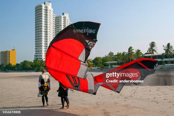 mann, der sein drachensegel in thailand trägt - thailand kite stock-fotos und bilder