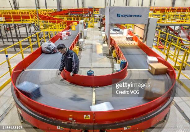 An employee sorts parcels at a logistics base of SF Express ahead of the Chinese New Year, the Year of the Rabbit, on January 13, 2023 in Yuncheng,...