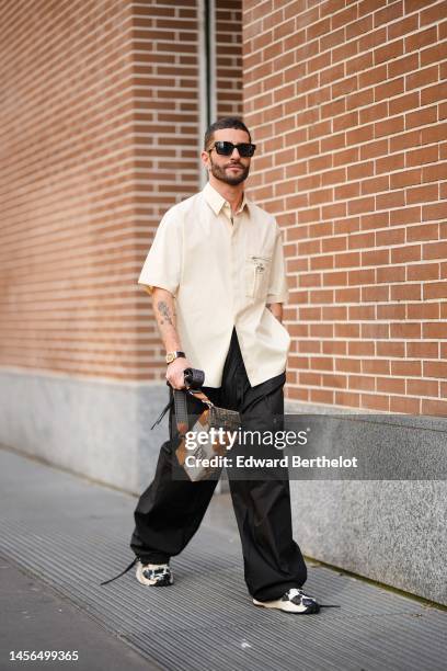 Pelayo Diaz wears black squared sunglasses from Fendi, diamond and silver earrings, a white latte oversized short sleeves shirt from Fendi, a large...