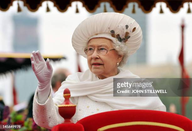 Britain's Queen Elizabeth II waves from the royal barge 'Spirit of Chartwell' as it sails past the Houses of Parliament during the Thames during the...