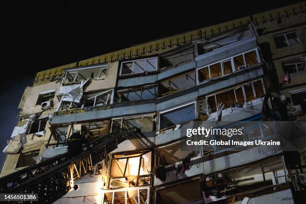 Rescuer climbs a ladder of a fire engine to one of the damaged apartments after a missile strike on January 14, 2023 in Dnipro, Ukraine. On January...