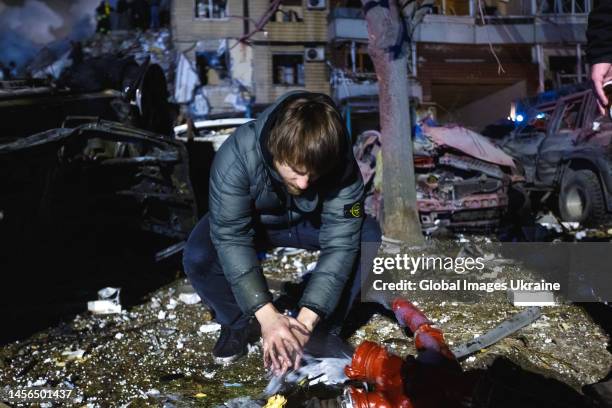 Man washes his hands near a high-rise residential building partially destroyed by a missile strike on January 14, 2023 in Dnipro, Ukraine. On January...