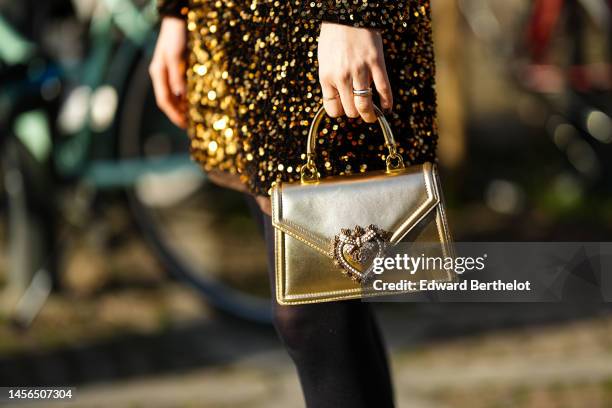 Guest wears a gold sequined long sleeves / short dress, a gold shiny leather handbag, black tights, outside MSGM, during the Milan Menswear...