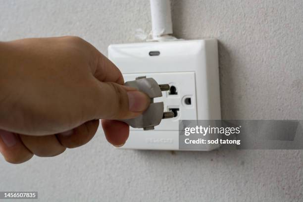 electric power plug in a hand and inserting into power wall socket - electric shock stock pictures, royalty-free photos & images