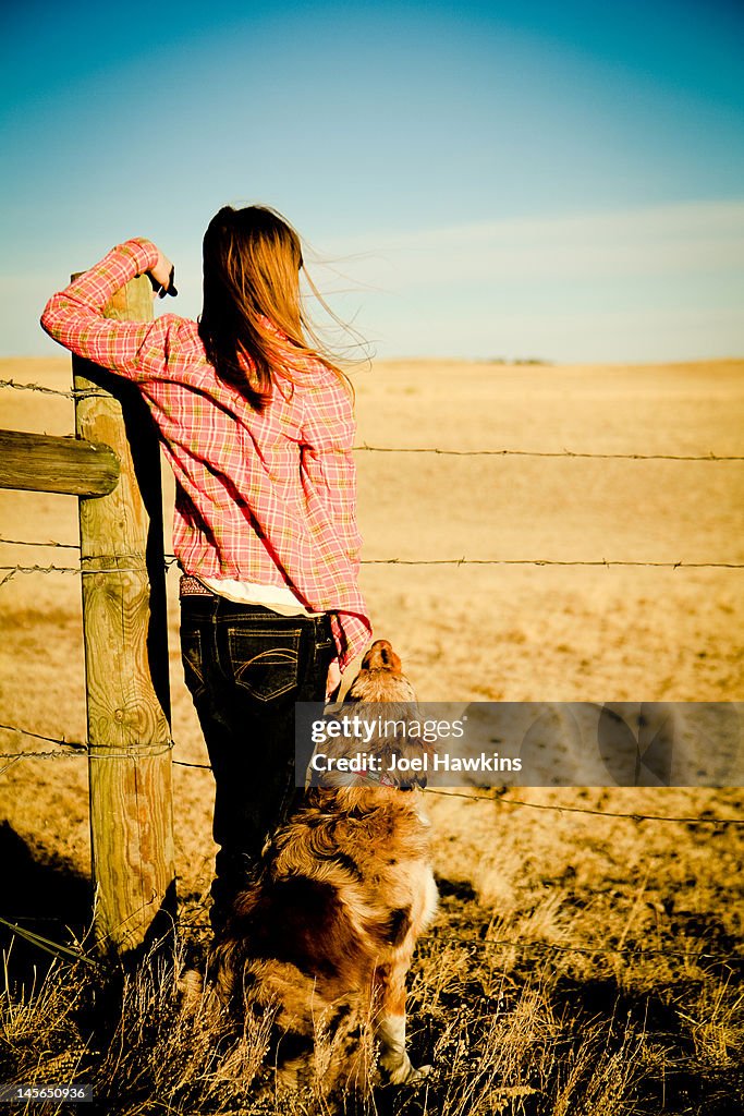 Girl and dog looking over fence